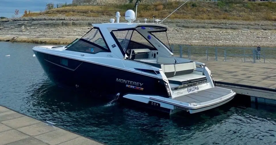 Luxury wake boat docked on the water with sleek black and white design.