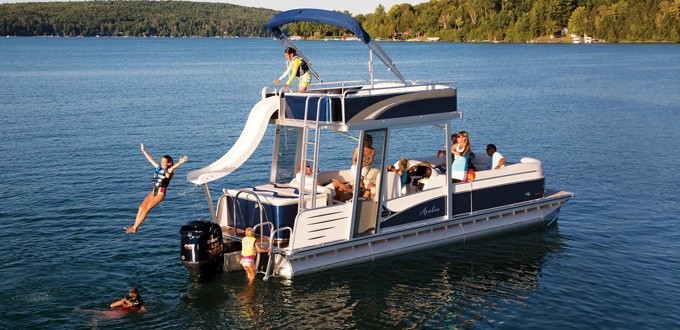 Yacht anchored near rocky shoreline – A white yacht close to the shore with two people standing on the flybridge waving.
